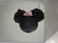 a minnie mouse head hanging from the side of a white wall with pine cones on it