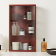 a shelf with soaps and lotions on it next to a black bowl in front of a white wall