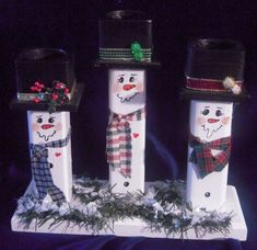 three snowmen with hats and scarves on their heads