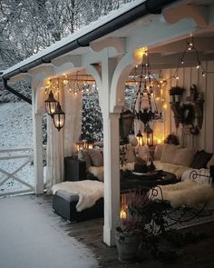 an outdoor living room with lights on the ceiling and furniture in the snow covered area