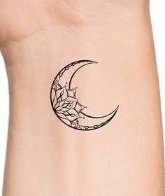 a small tattoo on the side of a woman's arm with a crescent and flowers