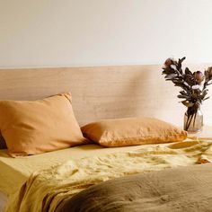 a bed with two pillows and a vase filled with flowers