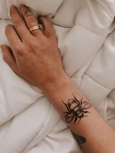 a woman's hand with a tattoo on it laying in bed under a blanket