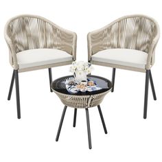 two wicker chairs and a table with flowers on it, both sitting side by side