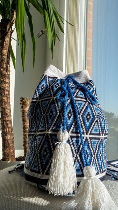 a blue and white bag sitting on top of a table next to a potted plant