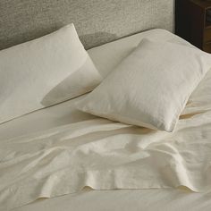 two white pillows sitting on top of a bed next to each other in front of a night stand