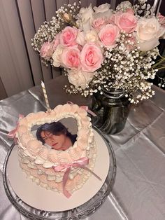 a heart shaped cake sitting on top of a table next to a vase filled with flowers