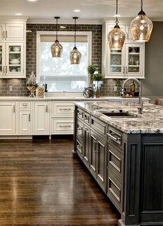 a large kitchen with white cabinets and marble counter tops, along with wooden flooring