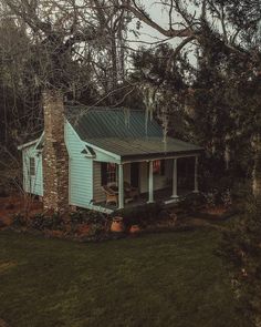 a small blue house sitting on top of a lush green field