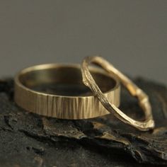 two gold wedding rings sitting on top of a piece of driftwood, ready to be married