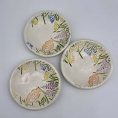 three small plates with flowers painted on them