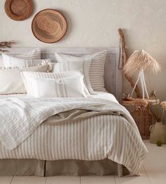 a bed with white and beige striped comforter in a bedroom next to two baskets on the wall