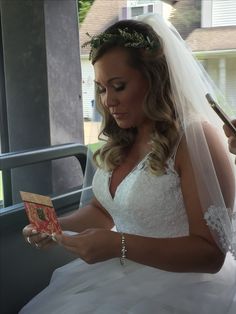 a woman in a wedding dress is reading a book while holding a pen and wearing a tiara