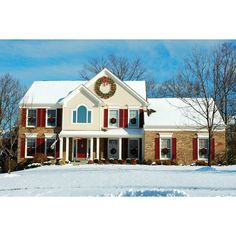 a large white house with red shutters and wreath on the front