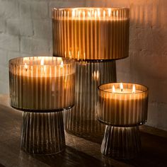 three glass candles sitting on top of a wooden table