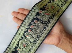 a hand holding a black and gold tie with dragon designs on it's side