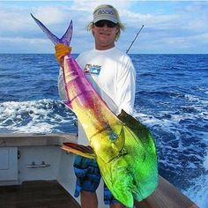 a man on a boat holding a colorful fish