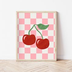 an art print with two cherries on a pink checkered tablecloth background in a wooden frame