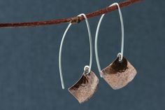 Hand formed sterling silver open hoops in an almond shape with dangling hammered copper squares, in a diamond shape. These light weight copper earrings have a light patina that brings out an earthy warm quality. Modern and a bit rustic! These earring are 1 3/4 inches (4.5 cm) long in the front, the back hangs a bit longer. The copper square is 5/8 x 5/8 inches (16 mm) All earrings come with clear earring stoppers. All of my designs are created by me, including all the metal components like ear w Minimalist Hammered Copper Jewelry, Handmade Modern Copper Jewelry, Modern Handmade Copper Jewelry, Hoop Silver Earrings, Simple Silver Earrings, Hammered Copper Earrings, Clear Earrings, Hammered Earrings, Earrings Diamond