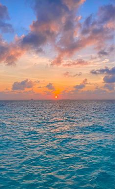 the sun is setting over the ocean as seen from a boat in the water with clouds