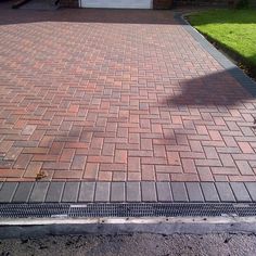 a red fire hydrant sitting on the side of a brick road next to a driveway