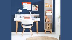 a white desk sitting in front of a blue wall next to a book shelf filled with books