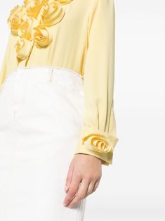 Created with a crepe texture and adorned with delicate floral appliqué, this long sleeve shirt features a classic collar and a concealed front button fastening.blending modern flair with timeless elegance. Mother-of-pearl buttons grace the concealed placket, while crochet and loop closures adorn the cuffs for added luxury. Brighten Up Your Wardrobe Today!Bring the sunshine everywhere you go with our vibrant crepe cotton blouse in bright yellow, adorned with romantic 3D flowers blooming along the front buttoned placket and cuffs of the long sleeves. Designed to elevate your style, this designer flower shirt features a fold-over collar for added flair, ensuring you stand out in every crowd. It's the perfect choice for adding a pop of color and whimsy to your 9-to-5 wardrobe, and even transit Designer Button-up Tops For Spring, Designer Long Sleeve Spring Blouse, Designer Long Sleeve Blouse With Ruffles, Designer Spring Tops With Ruffles, Designer Ruffled Tops For Spring, Chic Long Sleeve Shirt For Spring, Designer Ruffle Tops For Spring, Feminine Long Sleeve Shirt For Spring, Spring Formal Feminine Shirt