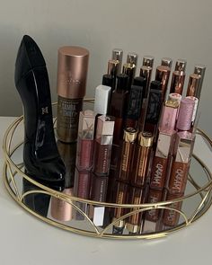 an assortment of lipstick and high heel shoes on a gold plated holder with mirror