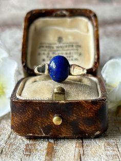 A beautiful vintage lapis lazuli solitaire ring crafted in 9 carat yellow gold.  The focal point of this lovely ring is an oval cabochon cut lapis lazuli gemstone known for its deep rich blue hue with scattered gold flecks reminiscent of a midnight starry sky!  The smooth polished surface of the lapis lazuli adds to its charm, softly reflecting light in an understated manner.  The yellow gold band perfectly compliments the rich regal blue gemstone enhancing the gold flecks within the stone creating a harmonious and cohesive look.  In very good vintage condition with minimal light wear and 9ct gold hallmark to inner shank.  There is some movement to the stone within its setting, however it is fully secure.  A lovely ring with a timeless appeal and unique characteristics which is sure to mak Art Deco Oval Cabochon Gemstone Jewelry, Timeless Oval Cabochon Sapphire Ring Gift, Timeless Cabochon Sapphire Ring Gift, Timeless Gift Sapphire Cabochon Ring, Classic Domed Sapphire Ring Gift, Classic Blue Domed Jewelry, Yellow Gold Lapis Lazuli Ring With Polished Finish, Classic Sapphire Oval Cabochon Jewelry, Vintage Sapphire Ring With Oval Cabochon