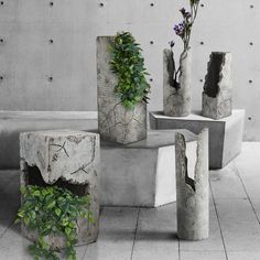 four cement vases with plants growing out of them on top of a tiled floor