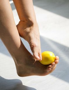 a person holding a lemon in their right hand and touching it with her left foot