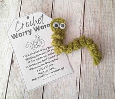 a crochet wormy worm on top of a piece of paper next to a sign