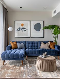 a living room with blue couches and pictures on the wall above them, along with a coffee table