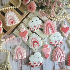 decorated cookies with pink and white icing are on a table next to some flowers