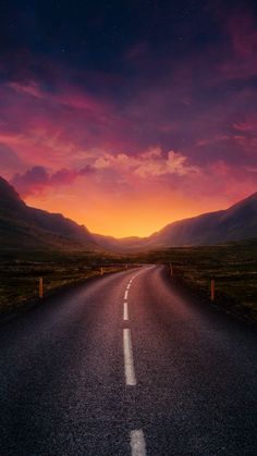 an empty road in the middle of nowhere at sunset with mountains in the back ground