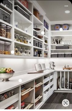 a kitchen with white cabinets and shelves filled with food