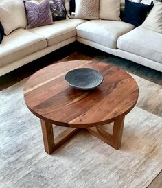 a wooden table sitting on top of a rug in front of a white sectional couch