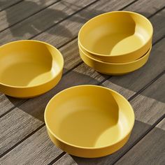 three yellow bowls sitting on top of a wooden table