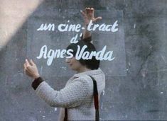 a woman standing in front of a chalkboard with her hand up to the sky