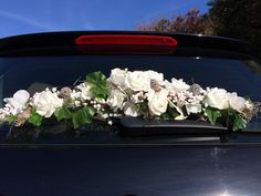 white flowers and greenery sit on the hood of a car