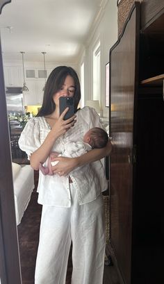 a woman holding a baby in her arms while taking a selfie with the phone