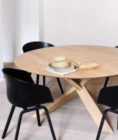 a wooden table with black chairs and a white hat on it's center piece