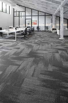 an empty office with desks and chairs in the middle of it, along with large windows