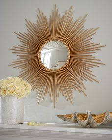 a sunburst shaped mirror above a mantle with flowers