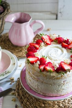 there is a cake with strawberries on the top and pink saucer next to it