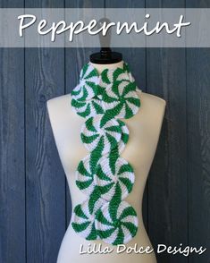 a green and white crocheted scarf on a mannequin torso with the words peppermint written across it