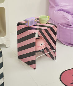 a pink pig in a black and white striped box on the floor next to a purple bean bag