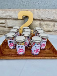 a wooden tray topped with lots of jars filled with jam on top of a table