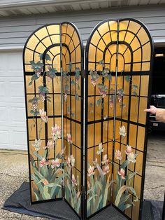 a hand is pointing at an ornate stained glass screen with flowers and leaves on it