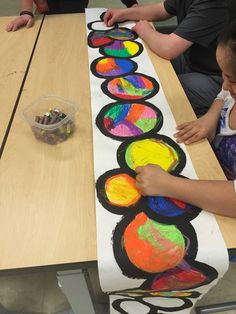 children are sitting at a table making art